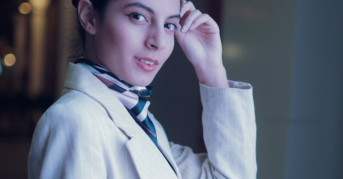 Portrait of a stylish woman in a light suit and scarf, posing outdoors at night in Dubai.