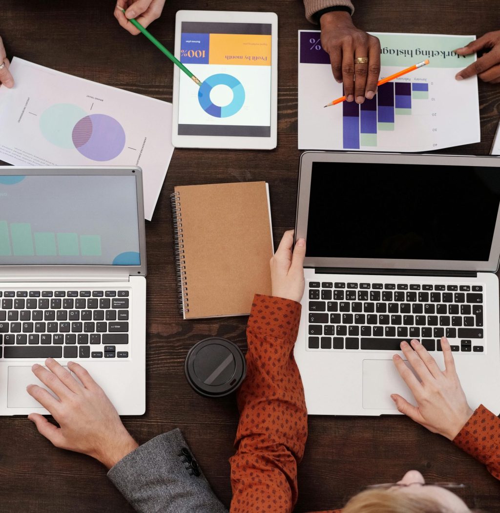 Overhead view of a team discussing digital marketing strategies with laptops and charts.