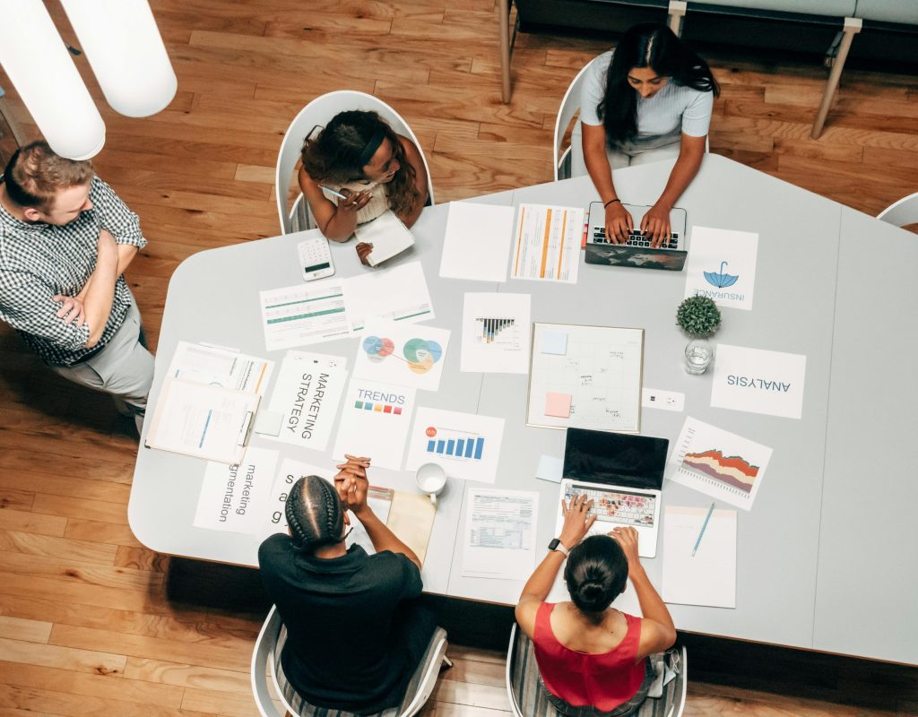 A diverse group working on marketing strategies with charts and laptops in an office setting.